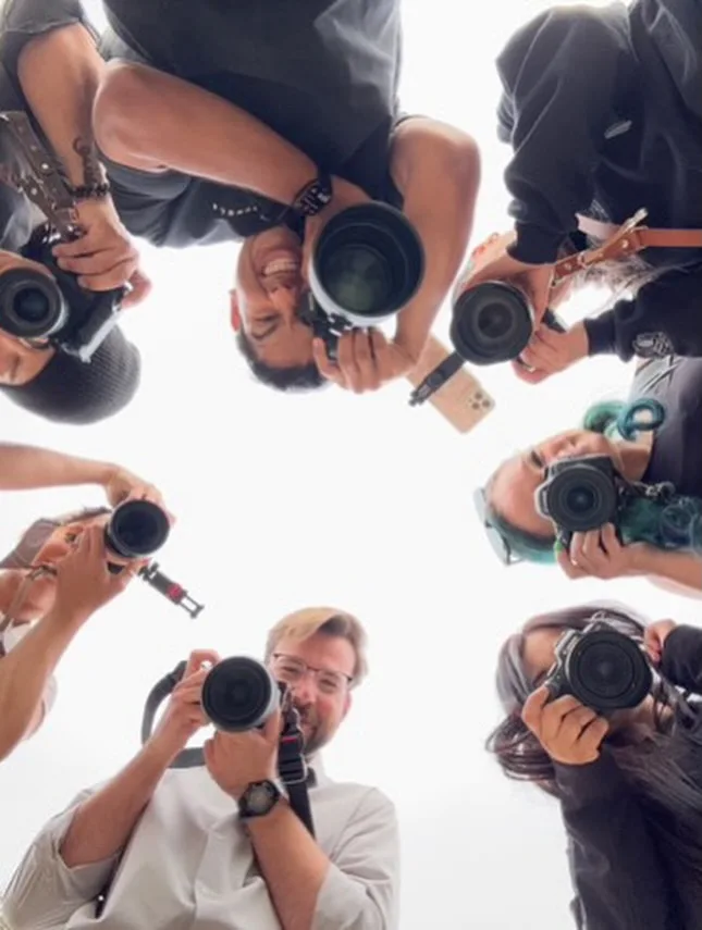 Group of photographers looking down into the camera in a circle.